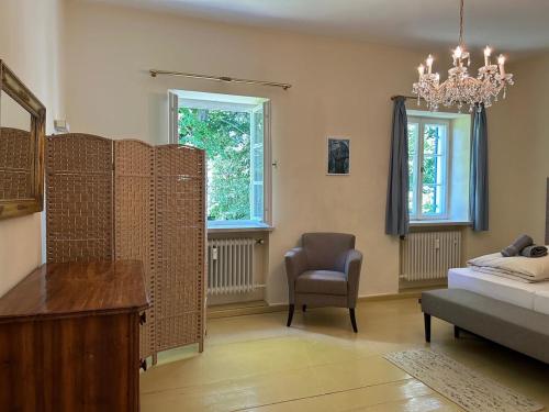 a bedroom with a bed and a chair and a chandelier at Ferienwohnung Villa Victoria mit grandiosem Seeblick und Gartennutzung in Jugendstil Villa in Gstadt am Chiemsee
