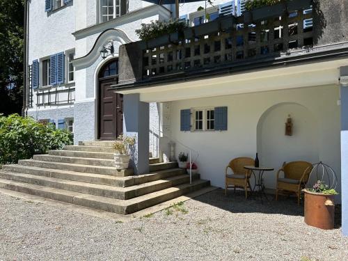 a building with stairs and a balcony with a table at Ferienwohnung Villa Victoria mit grandiosem Seeblick und Gartennutzung in Jugendstil Villa in Gstadt am Chiemsee