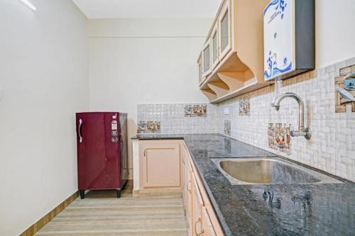 a kitchen with a sink and a red refrigerator at Ruby Hotel Apartments in Kakkanad