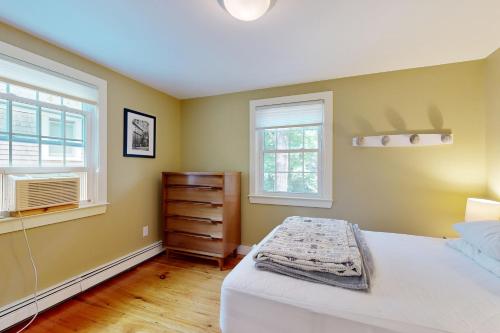 a bedroom with a bed and a dresser and two windows at Trailview Manor in Wellfleet