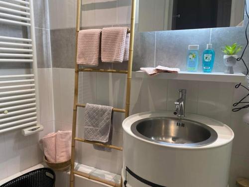 une salle de bain avec un lavabo et une étagère avec des serviettes dans l'établissement Comme une évidence, à Fécamp