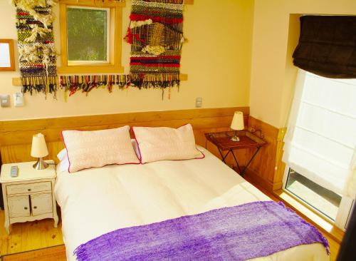 a bedroom with a bed with two pillows and a window at Casa Kalfu Hotel Boutique in Puerto Varas
