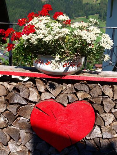 a red heart sitting on a table with flowers at Alpenferienwohnung Strickner in Neustift im Stubaital