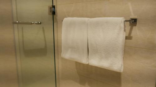a shower with a glass door and a towel at Eaton Residence KLCC - KL SUITE in Kuala Lumpur