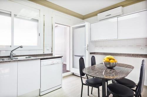 a kitchen with a table with chairs and a bowl of fruit at Stay U-nique House Torre Damians in Barcelona