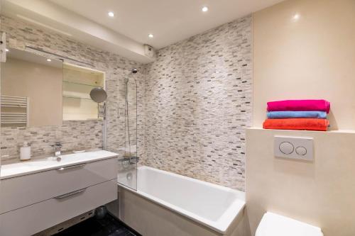 a bathroom with a white tub and a sink at TANIT Piscine, 6 couchages, Parking in Antibes
