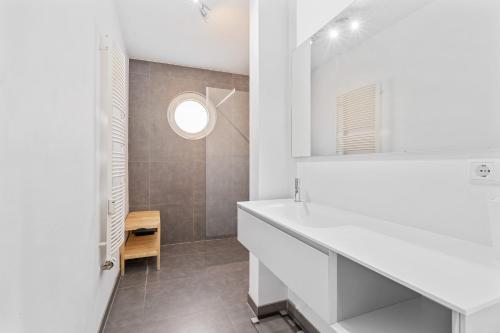 a white bathroom with a sink and a mirror at Modern Lux Apartment with Balcony in Luxembourg in Luxembourg