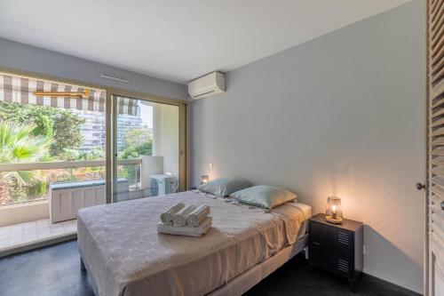 a bedroom with a large bed and a large window at TANIT Piscine, 6 couchages, Parking in Antibes