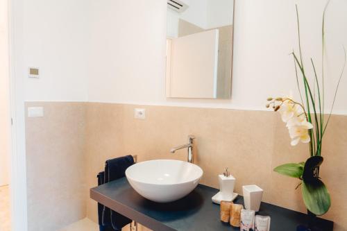 La salle de bains est pourvue d'un lavabo et d'un vase avec des fleurs. dans l'établissement Loli Trulli - Guest House, à Castellana Grotte