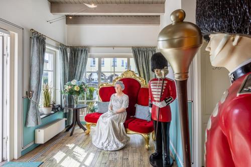 a woman sitting on a red chair next to a mannequin at The Little Britain Inn Themed Hotel One of a Kind In Europe in Vettelschoß
