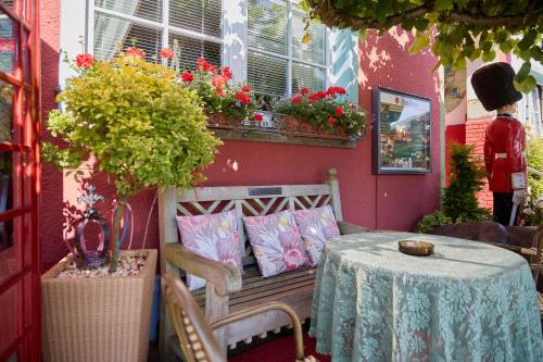 a table and a bench with a table and flowers at The Little Britain Inn Themed Hotel One of a Kind In Europe in Vettelschoß