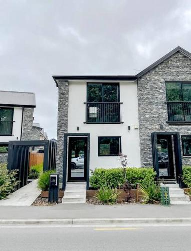 a white house with black windows and doors on a street at Hagley Park Townhouse in Christchurch