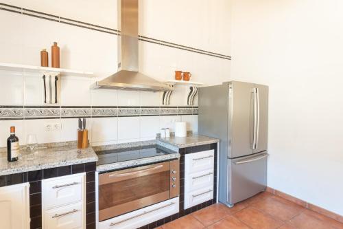 a kitchen with a stainless steel refrigerator and white cabinets at Retiro Sol - Casa Joni in Orba