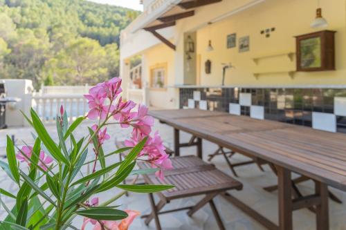 a wooden picnic table and a plant with pink flowers at Retiro Sol - Casa Joni in Orba