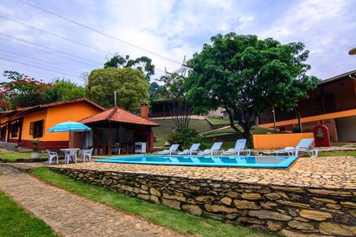 a swimming pool with lounge chairs and a house at Chácara Tedeschi in Monte Alegre do Sul