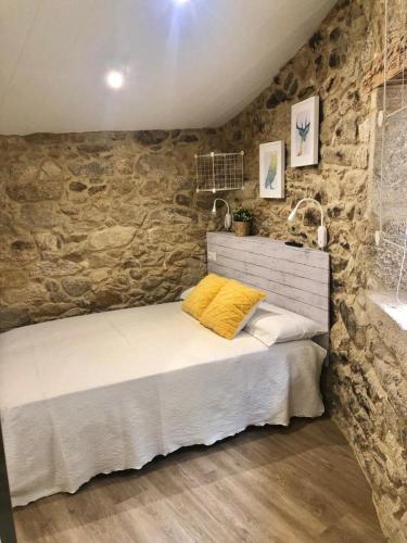 a bed in a room with a stone wall at Casa Arrabal in Oia