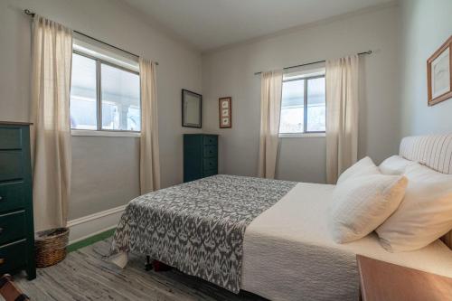 a bedroom with a bed and two windows at 7th Street Bungalow in Livingston
