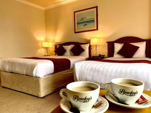a hotel room with two beds and two cups of coffee at An Cruiscin Lan in Spiddal