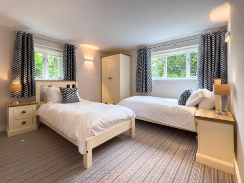 a bedroom with two beds and two windows at Rookery Cottage in Paignton