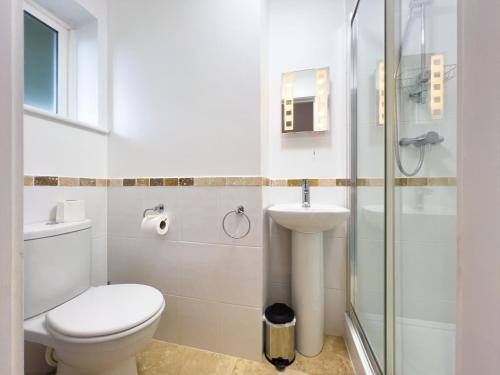 a white bathroom with a toilet and a sink at Rookery Cottage in Paignton