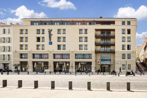a large building with people walking in front of it at Radisson Blu Hotel Marseille Vieux Port in Marseille