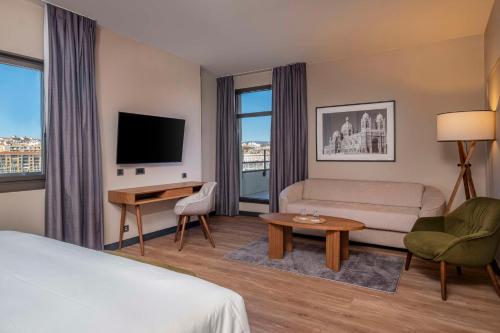 a hotel room with a bed and a couch and a tv at Radisson Blu Hotel Marseille Vieux Port in Marseille