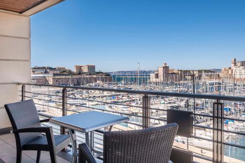 a balcony with chairs and a table and a view of a harbor at Radisson Blu Hotel Marseille Vieux Port in Marseille