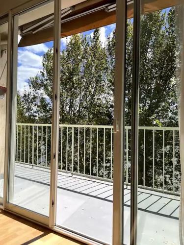 une porte vitrée ouverte d'un balcon avec des arbres dans l'établissement Appartement vue sur le Rhône, à Arles