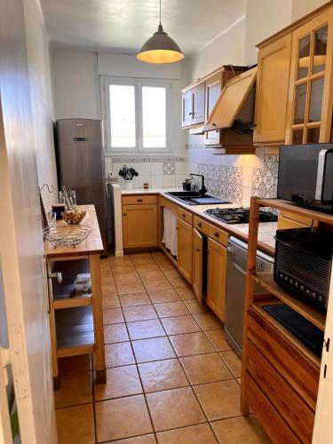 une cuisine avec des armoires en bois et un sol carrelé dans l'établissement Appartement vue sur le Rhône, à Arles