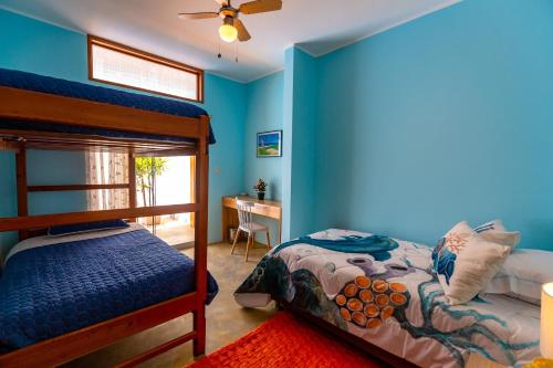 a bedroom with blue walls and a bunk bed and a desk at PUPUKEA HOUSE Mancora in Máncora