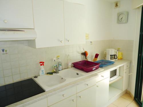 une cuisine blanche avec un évier et un micro-ondes dans l'établissement Bel Appartement 2 Pièces Climatisé proche Plages, à Cavalaire-sur-Mer