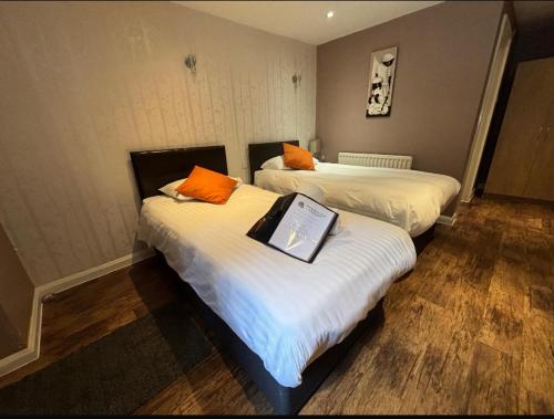 a room with two beds with orange pillows on them at Stay and Relax at The Yew Tree in Manuden