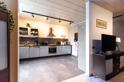 a large kitchen with white cabinets and a flat screen tv at Sander's Apartments Landstuhl in Landstuhl