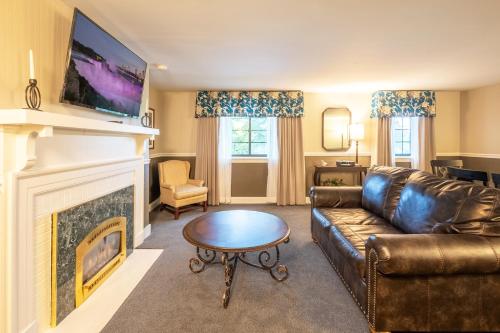a living room with a leather couch and a fireplace at Red Coach Inn in Niagara Falls