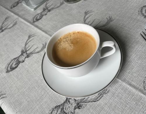 a cup of coffee on a plate on a table at The Old Manse B&B in Thurso