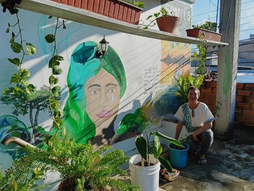 a woman sitting in front of a wall with a mural at Shoffi's House Backpackers in Tarapoto