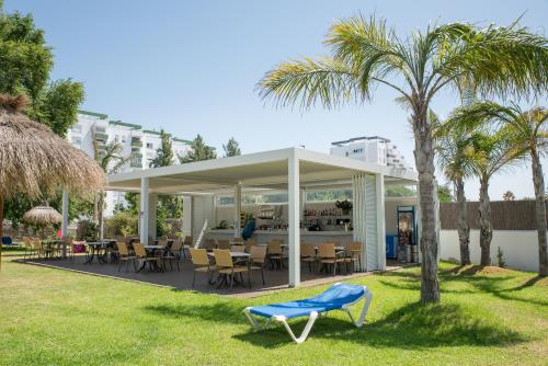a restaurant with a blue chair and palm trees at Hotel Puerto Bahía & Spa in El Puerto de Santa María