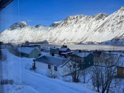 a village covered in snow with a mountain in the background at FeelSenja Gryllefjord Holiday House in Gryllefjord