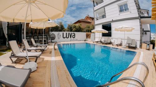 a pool with chairs and umbrellas next to a building at Luva Butik Otel in Didim