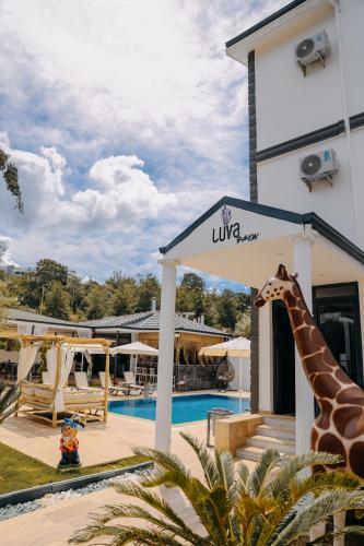 a giraffe standing next to a building with a pool at Luva Butik Otel in Didim