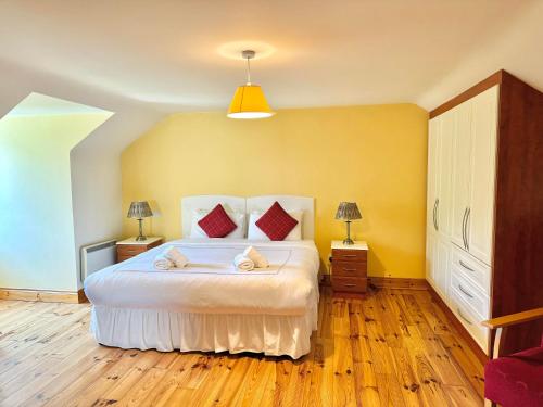a bedroom with a large white bed with red pillows at No 10 Ard Na Mara in Dingle