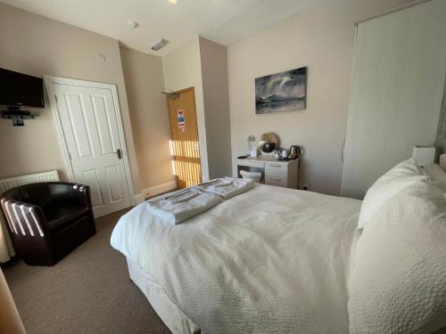 a bedroom with a white bed and a chair at Bwch yn Uchaf B&B in Llanuwchllyn