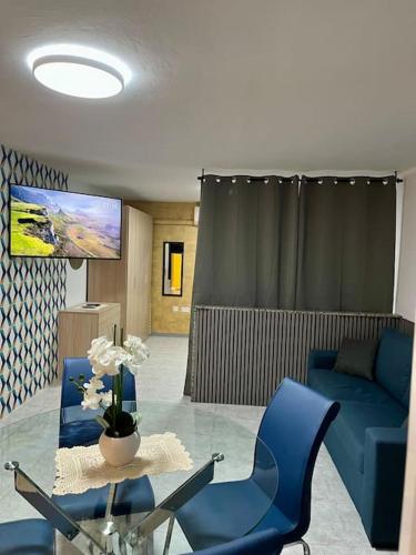 a living room with a blue couch and a glass table at Iris Chic Residence in Marsaskala