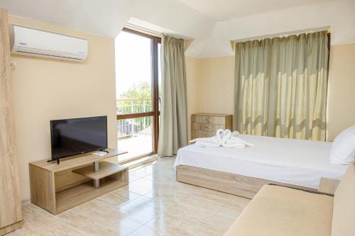 a hotel room with a bed and a television at Family Hotel Silitur in Ahtopol