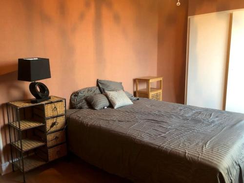 ein Schlafzimmer mit einem Bett und einer Lampe auf einem Nachttisch in der Unterkunft MAISON DE FAMILLE ENTRE MER ET CAMPAGNE à 5 MN DE LA PLAGE in Blainville-sur-Mer