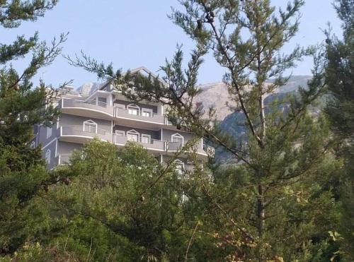 a building on top of a hill with trees at Oriente Sole in Dhërmi