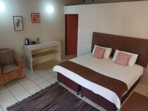 a bedroom with a large bed and a chair at Mokala Gastehuis in Lephalale