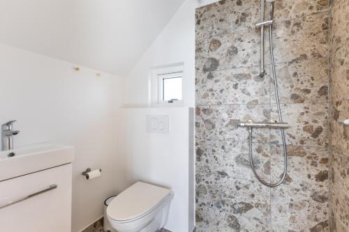 a white bathroom with a shower and a toilet at Bilberghus - Beyond Bed and Breakfast in Bjerregård