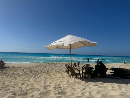 a group of people sitting under an umbrella on the beach at Grand hills in El Hamam