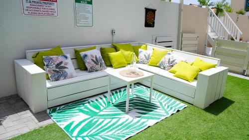 a white couch with yellow pillows and a table at 4BlessingsCuracao1 in Willemstad